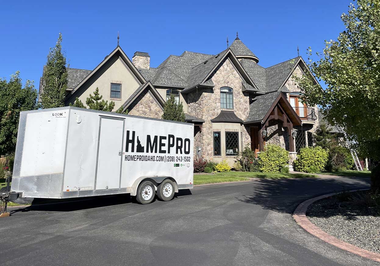 HomePro Idaho roof replacement work trailer parked at a large home before a new roof installation